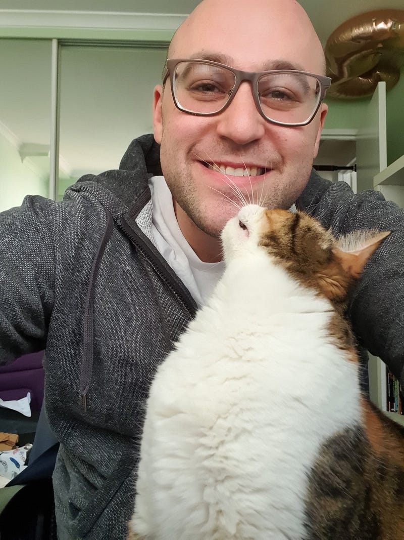 A bald person with a cat, showing a friendly demeanor